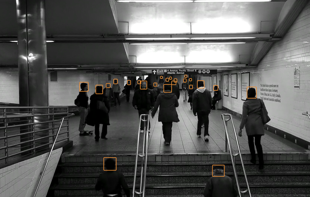 Image of a busy subway station with orange boxes highlighting detected faces.